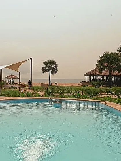 The resort's pool area seamlessly transitions to the beach, blurring the lines between the built environment and the natural coastline. The design prioritizes open spaces and ocean views for a perfect holiday setting.