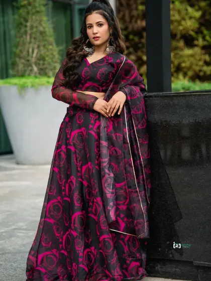 This pose is confident and stylish. The contrast of the bold floral pattern against the simple green background makes the outfit pop.
