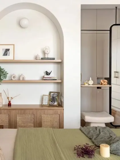 An inspiring bedroom design featuring an arched niche with wicker cabinetry and a sleek, floor-to-ceiling mirror that doubles as a dresser.