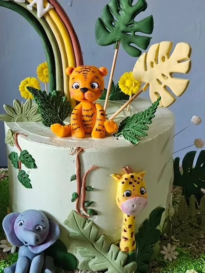 A close-up of the second jungle cake, featuring a cute tiger, elephant, and giraffe. The details on the fondant animals and the edible leaves bring the theme to life.