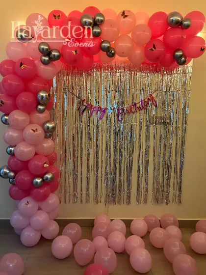 A simple L-shaped balloon garland in pink and silver against a fringe backdrop. This is a great way to decorate a small wall space at home.