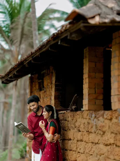 A shared, quiet moment during a village-themed pre-wedding shoot. The couple is seen reading a book together, highlighting a simple and personal connection.