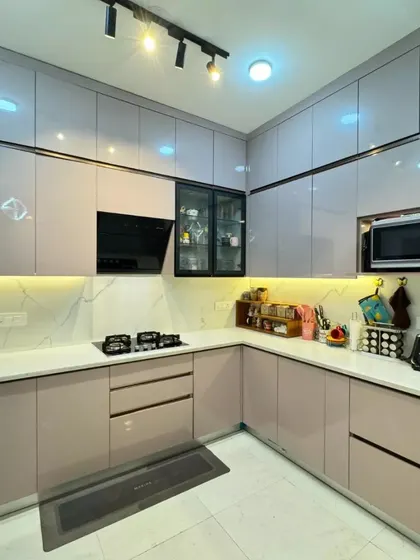 The L-shaped modular kitchen from our Gurgaon project, with dusty pink cabinets, a white marble backsplash, and integrated appliances for a seamless look.