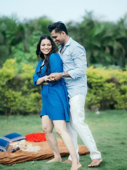 A candid shot of a couple dancing together barefoot in a park, sharing a laugh during their playful pre-wedding shoot.