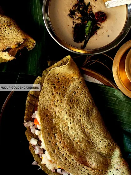 A healthy and flavorful Pesarattu, a savory crepe made from green gram batter. It is shown here filled with chopped onions and served with coconut chutney.