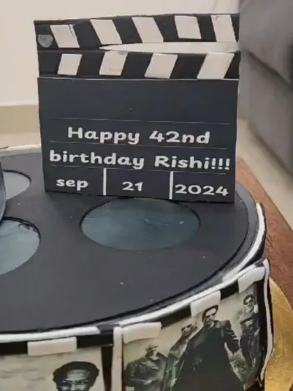 A close-up of the movie reel cake, showing the edible clapperboard with the birthday details.