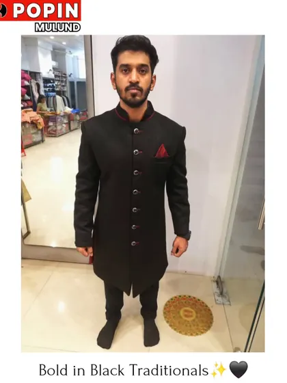 A client wearing a simple yet elegant black Indo-Western sherwani with a red pocket square for a pop of color. This is a versatile piece for any festive occasion.