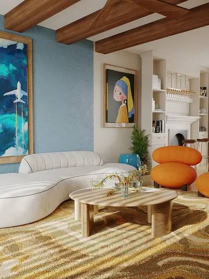 We also love to play with color. This vibrant living room design uses a bold blue wall, bright orange chairs, and eclectic artwork to create a space full of energy and personality, with wooden ceiling beams adding a rustic touch.