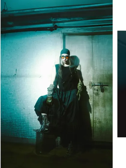 A wide shot with a strong teal color grade, showing the model in a dark, industrial setting. The dramatic lighting and pose create a powerful, futuristic silhouette.