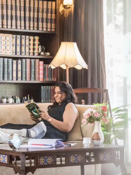 The bride enjoys a moment of peace, reading a book in a beautifully decorated room. This lifestyle shot adds a layer of personality and calm to their pre-wedding story.