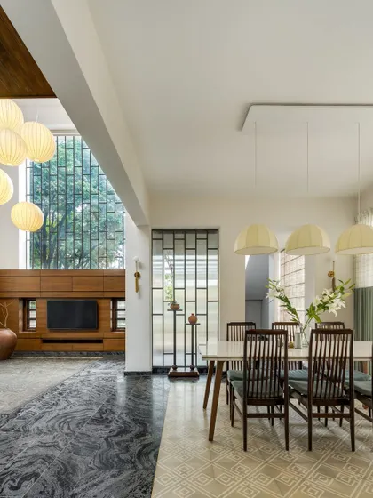 The open-plan living and dining area is designed as one continuous space. A double-height window in the living room and large openings in the dining area ensure the home is filled with light and connected to the outdoors.