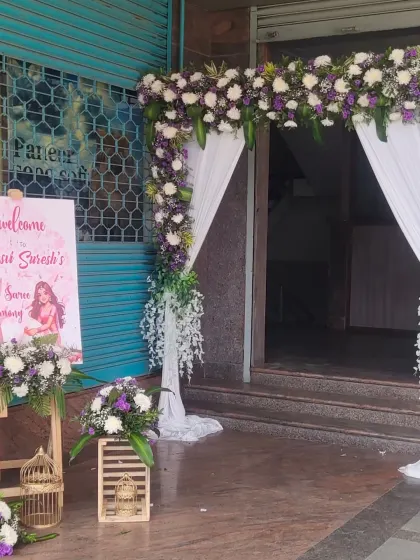 The entrance decor for a Half Saree ceremony, with a floral arch, welcome sign, and decorative birdcages.