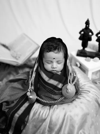 A close-up monochrome portrait of the baby as 'Rakhumai', emphasizing the peacefulness and innocence of the moment.