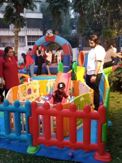 A lively party in full swing within one of my garden playzones. You can see kids enjoying the ball pit and bouncy castle while parents watch on, showcasing a fun and safe environment for everyone at the event.