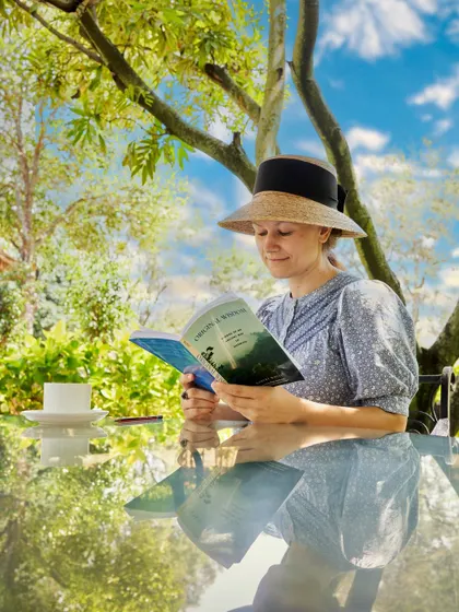 After a refreshing treatment, a guest unwinds in the garden with a book and a cup of herbal tea. These moments of quiet self-care are a vital part of the healing process.