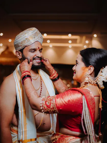 A playful moment between the couple, the bride gently pinching the groom's cheeks.