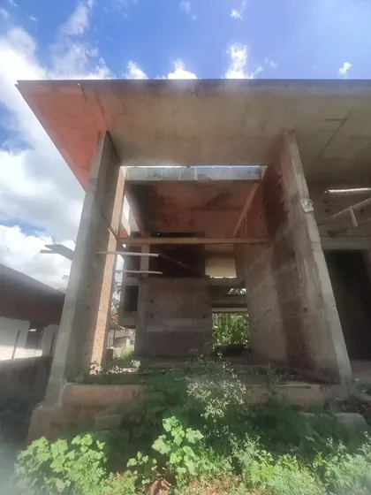 The bare shell of a farmhouse, designed with large, open portals to frame the views of the surrounding areca farm.