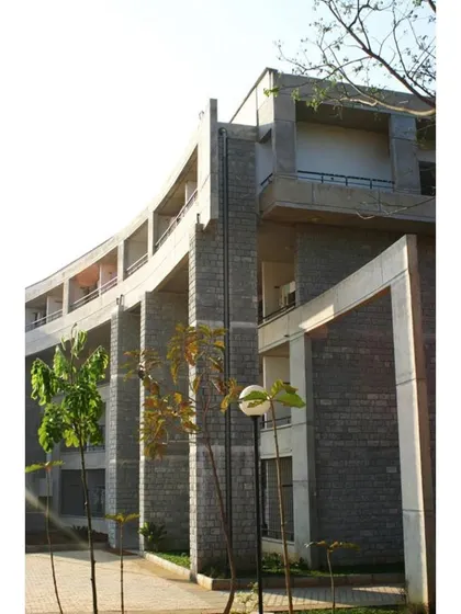 The curved hostel block at IIM-B, designed in two phases. The building's form wraps around a playground and preserves existing trees, creating a unique relationship between the architecture and the landscape.