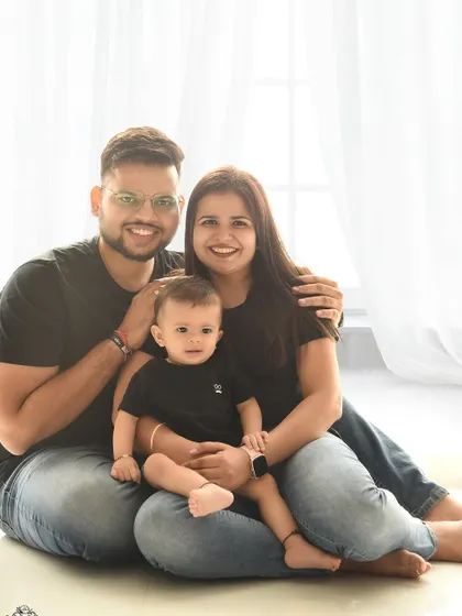 A perfect family portrait, smiling for the camera. The coordinated outfits and clean background create a polished and timeless look.
