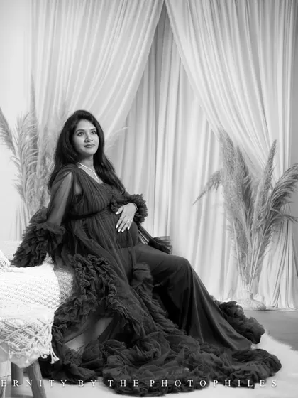 An elegant black and white shot of the mom-to-be seated in a flowing gown in our boho studio.