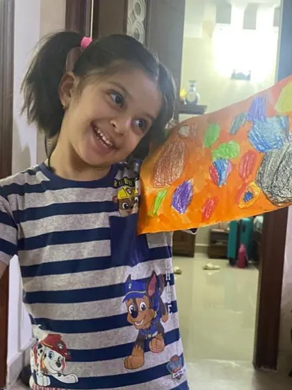 This happy student is showing off her dot-inspired artwork during an online class. We celebrate every child's unique creation and the story behind it.