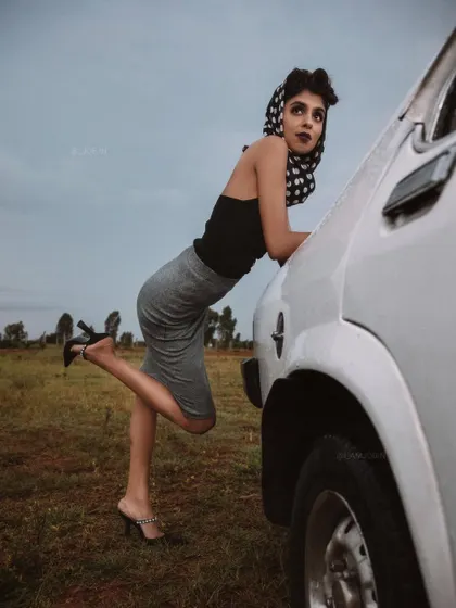 A dynamic pose from the 'BLANCH' shoot, using the vintage car as a key prop. The styling of the pencil skirt and bustier top creates a classic silhouette that defines the retro aesthetic of the series.