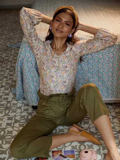 A playful and relaxed lifestyle shot for a fashion brand. The setting feels like a cozy bedroom, making the clothes feel accessible and perfect for everyday life.