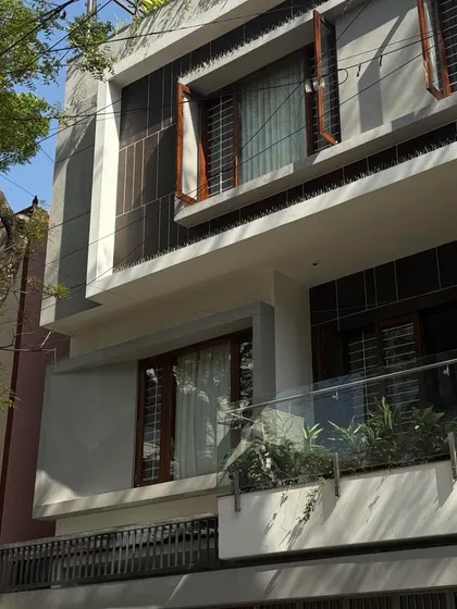 A detail of a multi-level facade, showing the combination of glass railings, wooden window frames, and textured gray panels.