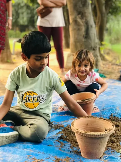 Two children work together on a potting activity. They are learning how to prepare the soil and pot a plant, a skill they can use for a lifetime.