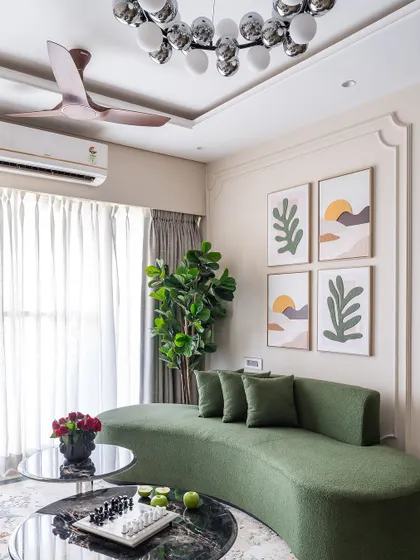 The centerpiece of the 'Modern Muse' living room is this custom-made curved sofa in a beautiful olive green fabric, complemented by a modern bubble chandelier and abstract wall art.
