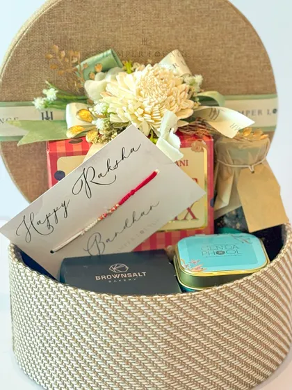 An inside look at the round Rakhi hamper, revealing the assortment of snacks, a jar of jam, and other curated items that make it a delightful surprise.