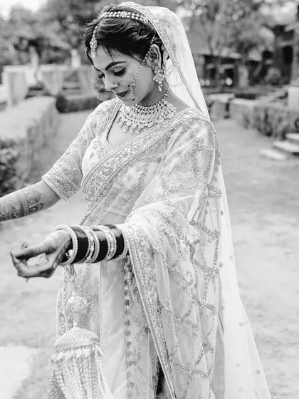 A timeless black and white portrait of a bride in a beautiful saree, adjusting her bangles.