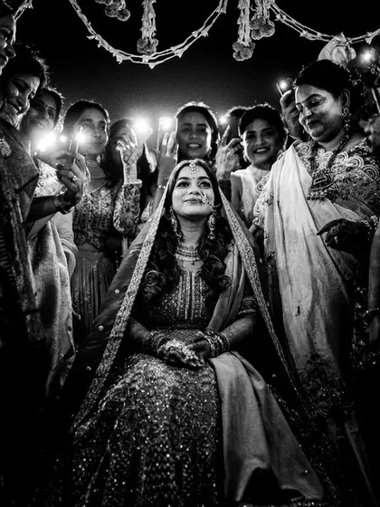 A powerful black and white shot of the bride during her entrance, surrounded by the women in her family. The lighting and composition create a dramatic and memorable image.