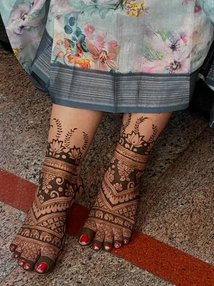 A full-coverage bridal foot design with intricate patterns and leafy motifs extending up the leg.