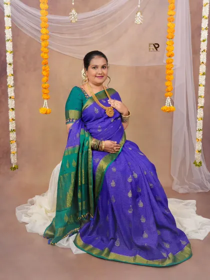 A classic portrait of the mom-to-be in a beautiful blue silk saree, standing gracefully in our studio setup with traditional marigold decorations.