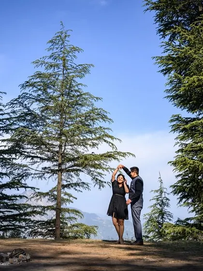 A joyful moment of dance amidst the tall deodar trees. This wide shot captures the couple's free-spirited love against a majestic natural backdrop.