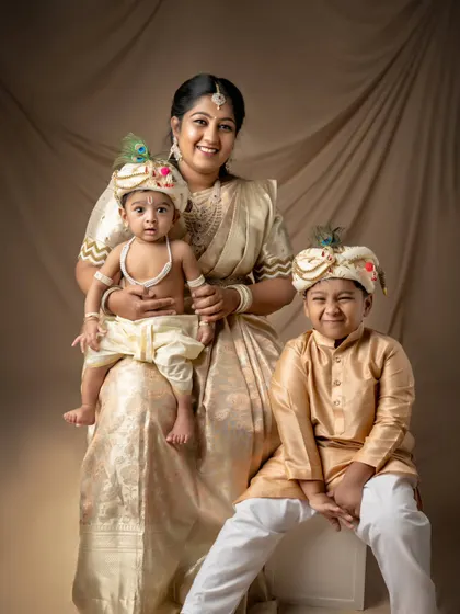 A mother with her two little Krishnas. The older brother's proud smile and the baby's cute expression make this a heartwarming family portrait.