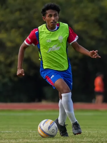 A player in a lime green bib shows his agility and speed during a drill. We focus on developing well-rounded athletes.
