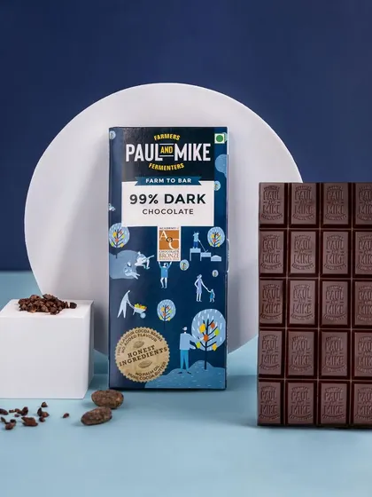 A 99% dark chocolate bar styled with geometric blocks against a deep blue background, creating a bold and sophisticated image.