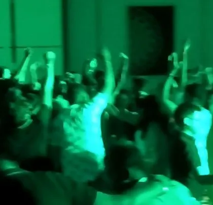 The crowd with their hands up, lit in bright green.