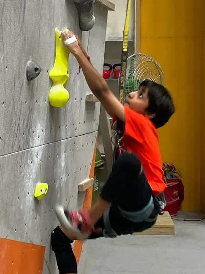 A young climber shows incredible focus and technique on an overhanging section of the wall.