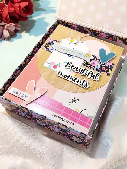 The inside of the bridal scrapbook box, showing the beautifully decorated album cover. The floral patterns and "beautiful moments" tag set the stage for the memories inside.