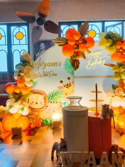 A warm, orange-toned "Wild One" safari theme with cute cartoon animal cutouts and a custom balloon arch.