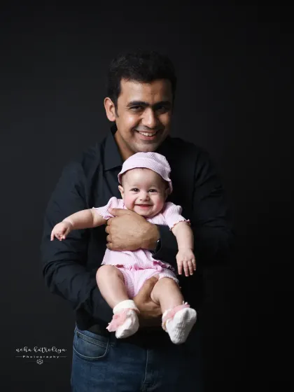 A proud father holding his smiling baby girl. This is a simple, classic portrait that beautifully captures the joy of fatherhood.