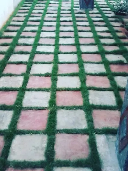 This pathway uses a checkerboard pattern of stone pavers and artificial grass. It's a stylish and practical design that is easy to keep clean.
