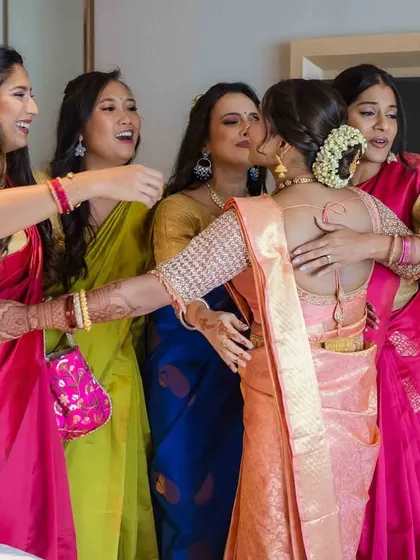 A big group hug. The bride is embraced by her best friends, a warm and emotional moment of love and support.