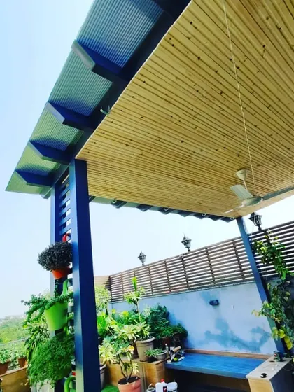 A beautiful pergola with a pine wood-clad ceiling and a duco-finished blue metal frame, creating a striking color combination.