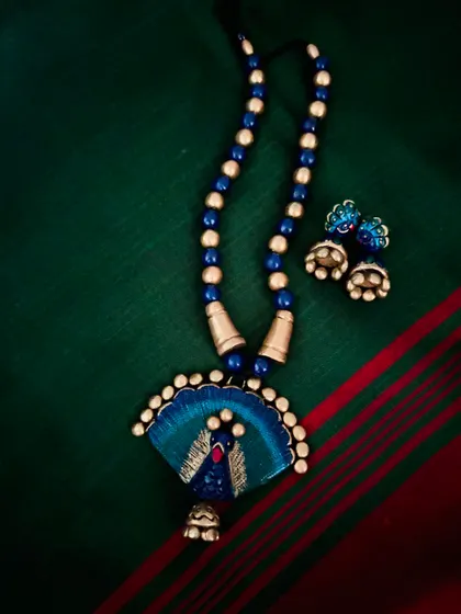 A beautiful peacock-fan-inspired terracotta set in shades of blue and gold. The delicate jhumka adds a touch of playful elegance.