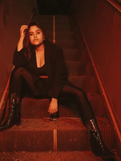 A powerful, wide-legged pose from the red-lit escalator shoot. The low angle and dramatic lighting create a commanding and unforgettable image.