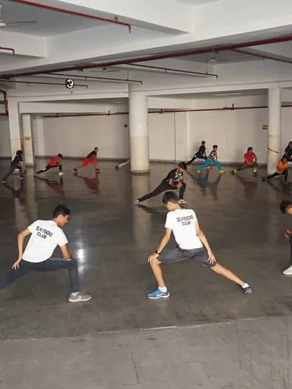 A full class of fencers participates in stretching exercises. Flexibility and proper warm ups are a critical part of our training regimen to maximize performance and prevent injuries.
